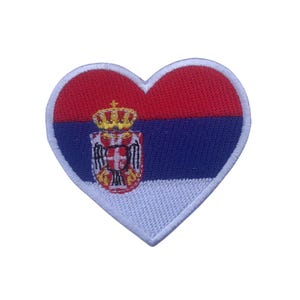 May include: A heart-shaped patch with the flag of Serbia. The flag features red, blue, and white stripes with the Serbian coat of arms in the center.
