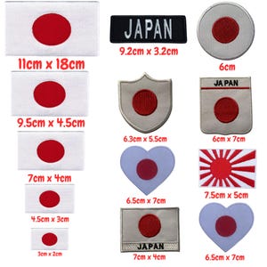 May include: A set of 10 iron-on patches featuring the Japanese flag in various sizes and shapes, including a rectangle, shield, heart, and circle. The patches are white with a red circle in the center. The text "JAPAN" appears on some of the patches.