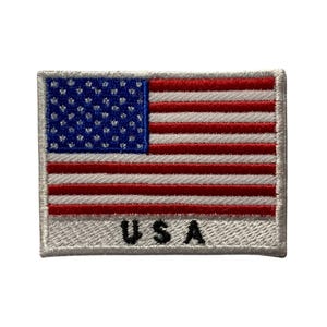 May include: A white embroidered patch featuring a red, white and blue American flag with the text "USA" underneath.