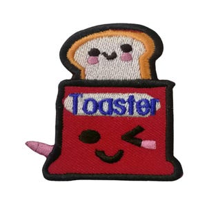 Può includere: Una toppa ricamata rossa di un tostapane sorridente con una fetta di pane all'interno. Il tostapane ha la scritta "Toaster" ricamata in blu.
