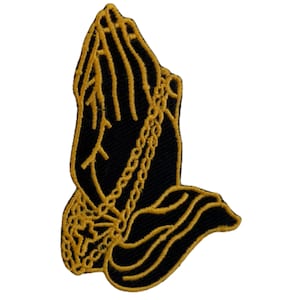 May include: Black embroidered patch with a gold outline of praying hands with a chain around the wrists.