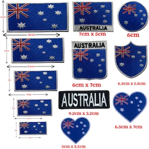 May include: A selection of Australian flag patches in blue and white. The patches display the Australian flag design, including the Union Jack and Southern Cross. Some patches are rectangular, circular, or heart-shaped, with the word "AUSTRALIA".