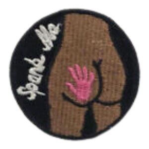 May include: Round patch with a black border and a brown center. The design features a stylized rear end with a pink hand and the words "Spend Me" in white cursive.