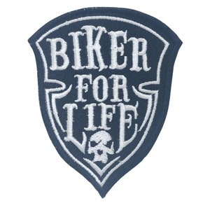May include: White embroidered patch with a black background in the shape of a shield. The patch says "Biker For Life" with a skull graphic at the bottom.