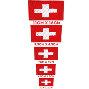 Può includere: Cinque bandiere svizzere ricamate in diverse dimensioni. Le bandiere sono rosse con una croce bianca al centro. Le dimensioni sono 11 cm x 18 cm, 9,5 cm x 4,5 cm, 7 cm x 4 cm, 4,5 cm x 3 cm e 3 cm x 2 cm.