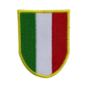 May include: A green, white and red embroidered patch with a yellow border in the shape of a shield.