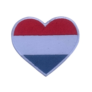 Puede incluir: Un parche en forma de corazón rojo, blanco y azul con los colores de la bandera holandesa.