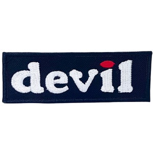 Op de afbeelding: Geborduurde patch met het woord "devil" in witte, vette letters. De marineblauwe rechthoekige patch heeft een kleine rode stip boven de letter "i".