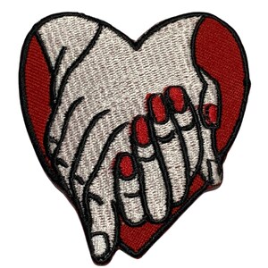 May include: An iron-on patch embroidered with two hands clasped together in the shape of a heart. The hands are white with black outlines and red nail polish. The heart is red.