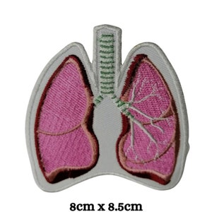 Könnte beinhalten: Gestickter Aufnäher, der ein Paar Lungen in Rosa und Braun mit weißem Rand darstellt. Der Aufnäher misst 8 cm x 8,5 cm. Das Design umfasst Luftröhre und Bronchien und zeigt anatomische Details.