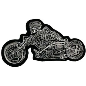 May include: Black and white embroidered patch of a skeleton riding a motorcycle. The motorcycle is detailed with a skull on the back tire.