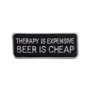 Op de afbeelding: Zwart-witte geborduurde patch met de tekst "Therapie is duur, bier is goedkoop".