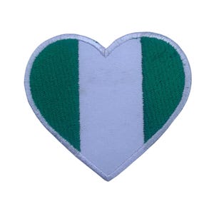 Può includere: Una toppa a forma di cuore con i colori della bandiera nigeriana. La toppa è verde, bianca e verde, con il bianco al centro.