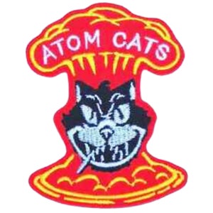 May include: An embroidered patch featuring a cartoon cat with a mischievous grin, surrounded by a red mushroom cloud with the text "ATOM CATS" in yellow.
