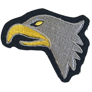 May include: A gray embroidered eagle head patch with a yellow beak and eye. The patch is on a black background.