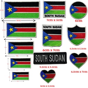 May include: A selection of embroidered South Sudan flag patches in various shapes. The patches feature the flag's design: black, red, green, blue, and a yellow star. Shapes include rectangles, circles, and a heart. Sizes range from 3cm to 18cm in length.
