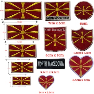 Op de afbeelding: Een verzameling geborduurde patches met de vlag van Noord-Macedonië. De patches hebben verschillende vormen, waaronder rechthoeken, een cirkel, een schild en een hart. Het vlagontwerp is rood met een gele zon. Maten variëren van 3 cm tot 18 cm.