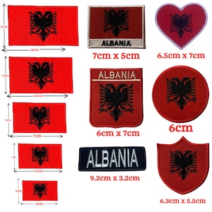 Pode incluir: Um conjunto de dez patches para passar a ferro com a bandeira albanesa em vários formatos e tamanhos. Os patches são vermelhos com uma águia bicéfala preta. Os patches incluem um coração, um círculo, um escudo e patches retangulares com a palavra "Albânia" impressa neles. Os patches variam em tamanho de 3 cm a 9,2 cm.