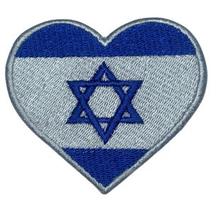 May include: A heart-shaped embroidered patch featuring the Israeli flag. The flag is blue and white with a blue Star of David in the center.