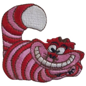 May include: A red and pink embroidered patch of the Cheshire Cat from Alice in Wonderland. The cat is grinning with a wide, toothy smile and has a curled tail.