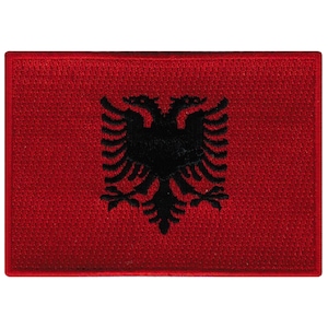 Może przedstawiać: Czerwona haftowana naszywka z czarnym dwugłowym orłem, symbolem narodowym Albanii.