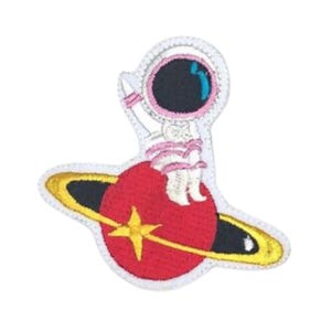 Puede incluir: Un parche bordado con un astronauta blanco sentado en un planeta rojo con un anillo amarillo a su alrededor. El astronauta lleva un casco rosa y una visera azul.