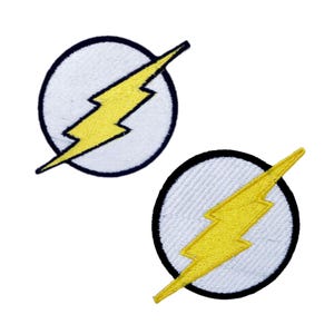 May include: Two embroidered iron-on patches featuring the Flash logo. The logo is a yellow lightning bolt inside a white circle with a black outline.