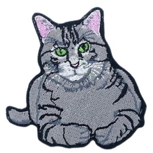 May include: Embroidered iron-on patch of a gray tabby cat with green eyes, sitting with its paws tucked in front of it.