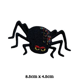 May include: Black spider embroidered patch with colourful details. The spider has eight legs and a large, round body with a colourful design. The patch measures 8.5 cm by 4.5 cm.