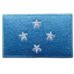 May include: A blue fabric patch with four white five-pointed stars. The patch is a representation of the flag of Micronesia.