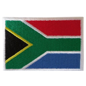 May include: Embroidered patch of the South African flag. The flag features a black triangle with a yellow border, a red stripe, a green stripe, and a blue stripe.