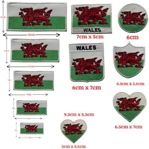 Può includere: Una collezione di toppe ricamate con la bandiera gallese e il drago gallese. Le toppe sono disponibili in varie forme e dimensioni, tra cui rettangolari, circolari, a scudo e a cuore. La toppa più grande misura 18 cm di larghezza e 11 cm di altezza.