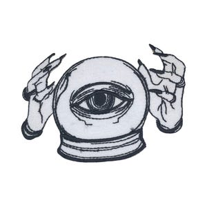 Peut inclure: Patch brodé noir et blanc d'une boule de cristal avec un œil à l'intérieur, tenu par deux mains avec des griffes.