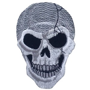 Könnte beinhalten: Weißer gestickter Totenkopf-Patch mit einem Riss-Design. Der Schädel hat einen schwarzen Hintergrund und einen weißen Umriss.