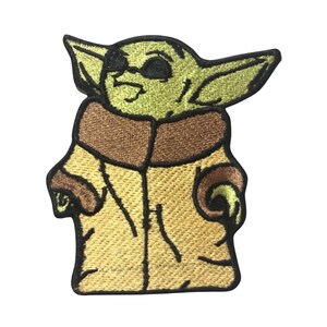 May include: Embroidered patch featuring a green character with large ears, wearing a brown and yellow coat and sunglasses.