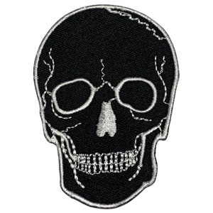May include: Black embroidered skull patch with white stitching. The skull has a detailed design with eye sockets, a nose, and a mouth.