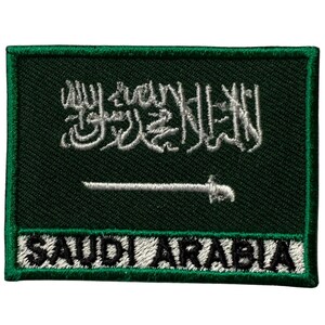 Puede incluir: Parche bordado verde con la bandera de Arabia Saudita. La bandera presenta una inscripción árabe blanca y una espada blanca sobre un fondo verde. Las palabras "SAUDI ARABIA" están escritas en letras blancas sobre un fondo negro.