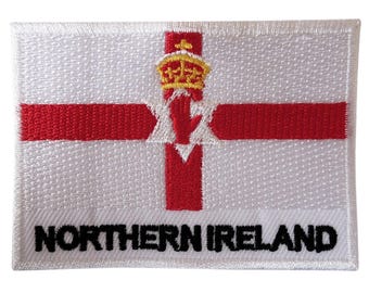 Könnte beinhalten: Rechteckiger, gestickter Aufnäher mit der Flagge Nordirlands. Das Design zeigt einen weißen Hintergrund, ein rotes Kreuz, eine rote Hand mit goldener Krone und den schwarzen Schriftzug "NORTHERN IRELAND".