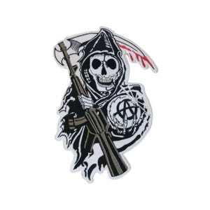 Può includere: Toppa ricamata in bianco e nero di uno scheletro incappucciato che tiene un fucile e un simbolo di anarchia. Lo scheletro indossa una tunica con cappuccio e ha una falce della morte dietro.