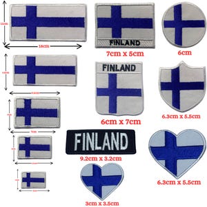 Puede incluir: Un conjunto de diez parches termoadhesivos con la bandera finlandesa en varios tamaños y formas. Los parches son blancos con una cruz azul y la palabra "FINLANDIA" está impresa en algunos de los parches. Los parches varían en tamaño de 3 cm x 3,5 cm a 9,2 cm x 3,2 cm.