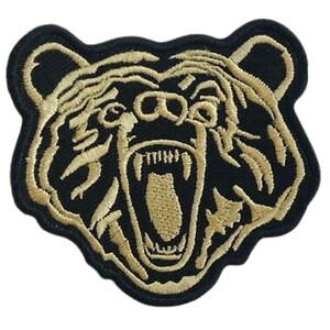 Op de afbeelding: Een gouden geborduurde patch van een berenkop met een open mond en scherpe tanden. De berenkop is zwart omrand.