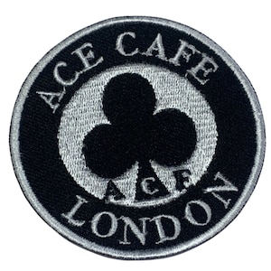 Puede incluir: Parche bordado en blanco y negro con el texto "ACE CAFE LONDON" y un trébol negro en el centro.