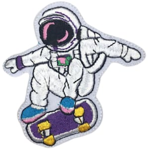 Puede incluir: Un parche bordado de un astronauta blanco con un casco morado y rosa, montando un monopatín morado con ruedas doradas.