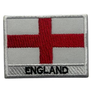 Puede incluir: Parche bordado con la bandera de Inglaterra. El diseño incluye una cruz roja sobre fondo blanco, con la palabra "ENGLAND" bordada en negro en la parte inferior. El parche tiene un borde blanco.