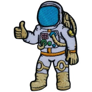 May include: Embroidered patch featuring a cartoon astronaut in a white spacesuit with gold accents, giving a thumbs-up gesture. The astronaut's helmet has a blue visor. The patch is suitable for jackets, bags, or other fabric items.