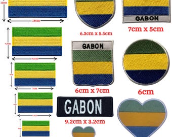 May include: A collection of embroidered patches featuring the green, yellow, and blue horizontal stripes of the Gabon flag in various shapes including rectangles, shields, circles, and hearts, with some patches displaying the text GABON.