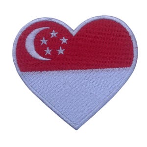 Puede incluir: Parche en forma de corazón con la bandera de Singapur. La mitad superior es roja con una luna creciente blanca y cinco estrellas. La mitad inferior es blanca. El parche tiene un borde blanco.