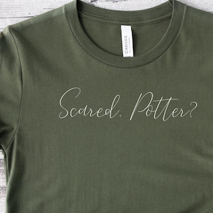 May include: A green t-shirt with the text "Scared. Potter?" in white lettering.