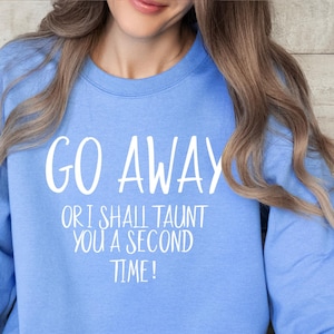 Könnte beinhalten: Hellblaues Sweatshirt mit dem weißen Text "GO AWAY OR I SHALL TAUNT YOU A SECOND TIME!". Das langärmlige Oberteil ist aus einem weichen Material und für Freizeitkleidung geeignet.