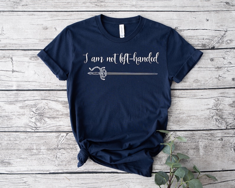 Pu&ograve; includere: Una maglietta blu navy con una grafica bianca di una spada e il testo "Non sono mancino".